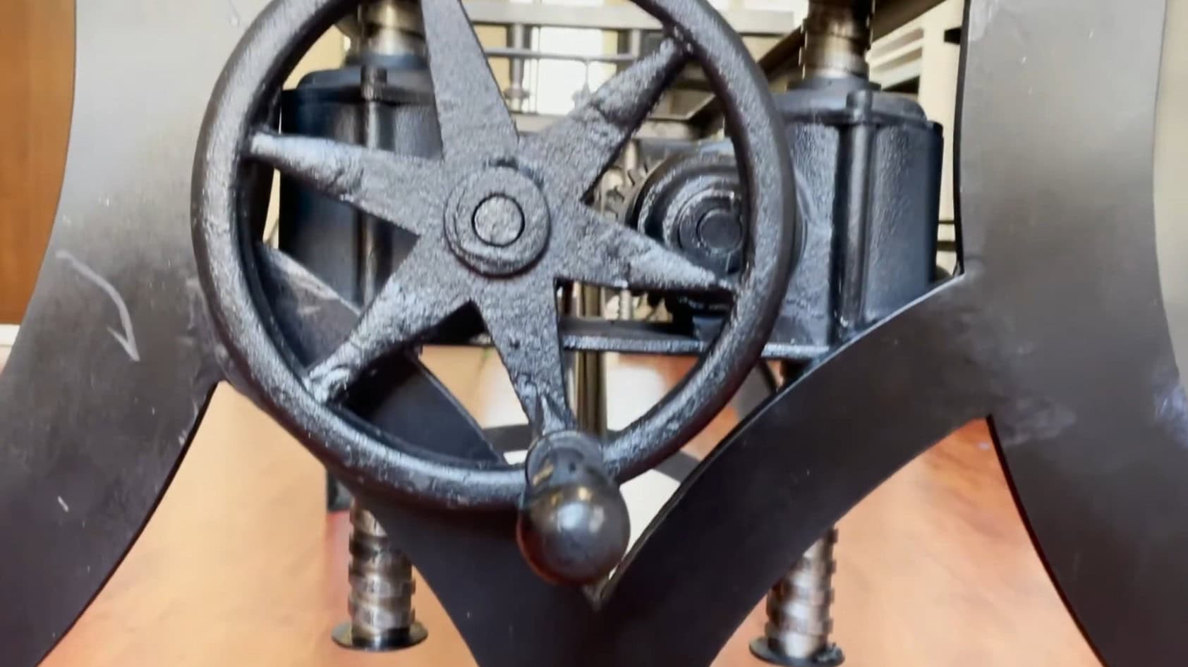Crank wheel on Indian-manufactured industrial crank table copy — unfinished cast iron, casting flash on spokes