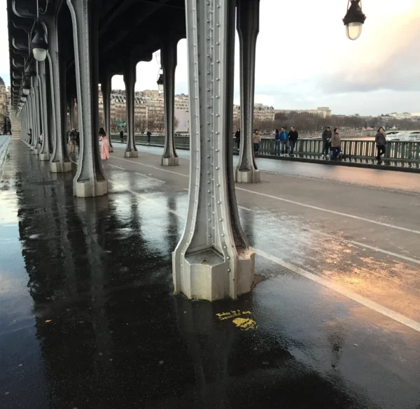 Pont de Bir-Hakeim bridge columns reflecting in wet pavement, Paris — riveted iron structure that inspired the French Column dining table base